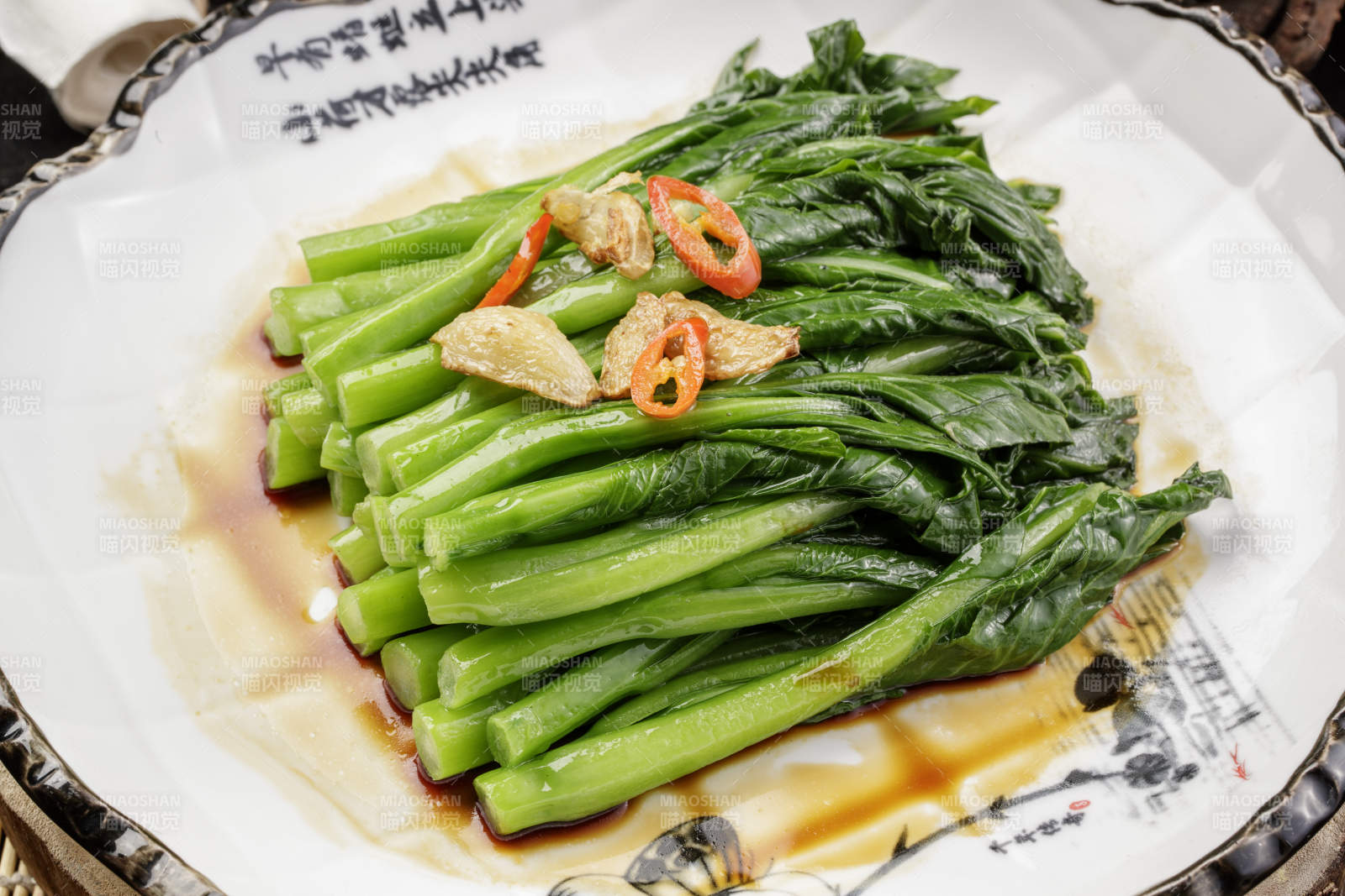 白色瓷盘装的炝炒芥蓝摆放在樟木砧板上图片