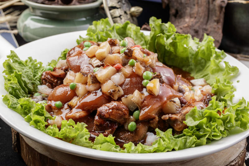 圆形瓷盘装的红扒大肘子摆放在樟木砧板上图片