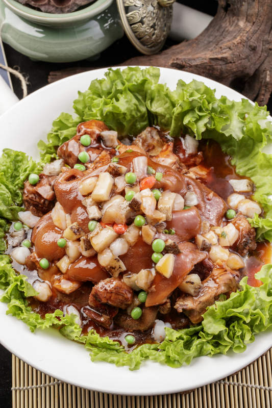 圆形瓷盘装的红扒大肘子摆放在樟木砧板上图片