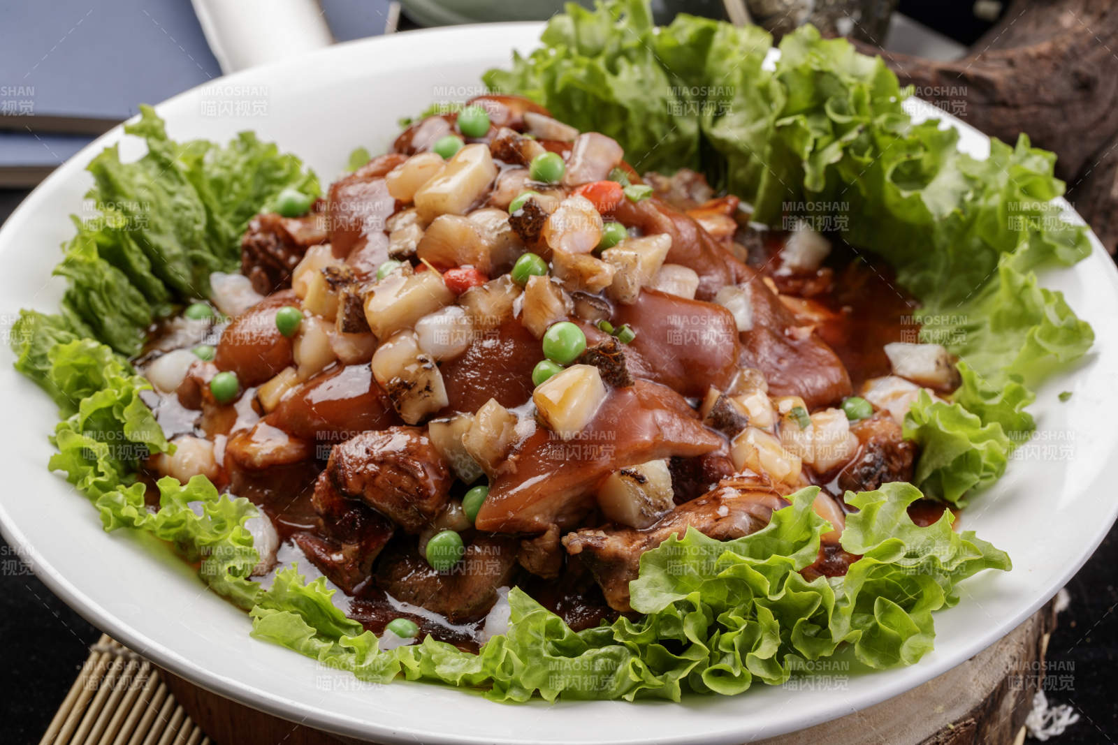 圆形瓷盘装的红扒大肘子摆放在樟木砧板上图片