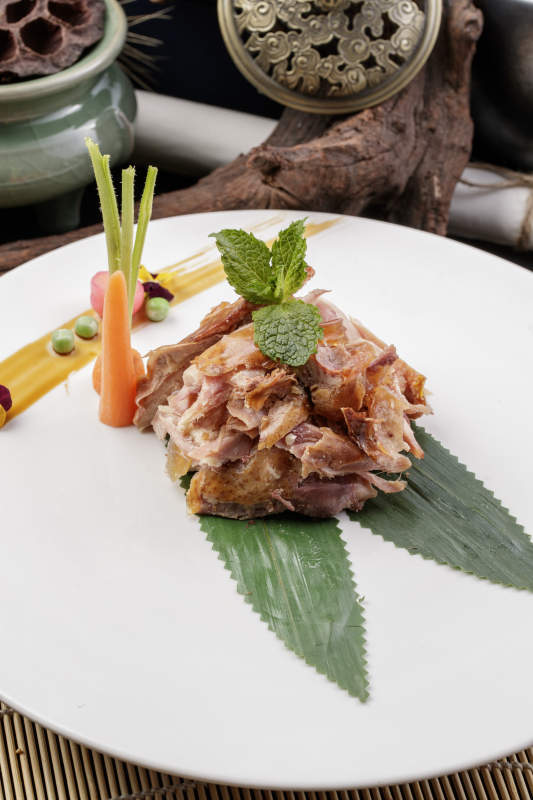 圆形白瓷盘装的风味手撕鸡摆放在寿司帘上图片