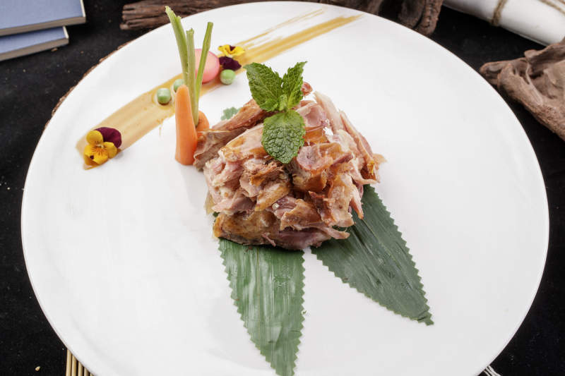 圆形白瓷盘装的风味手撕鸡摆放在寿司帘上图片