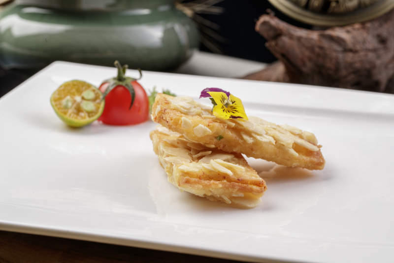 制作精良的北派鱼泥杏仁酥摆放在樟木砧板上图片