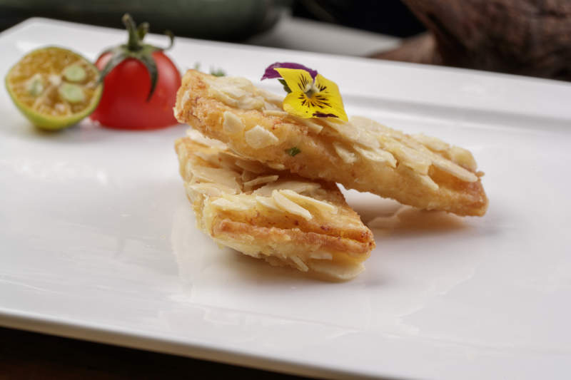 制作精良的北派鱼泥杏仁酥摆放在樟木砧板上图片