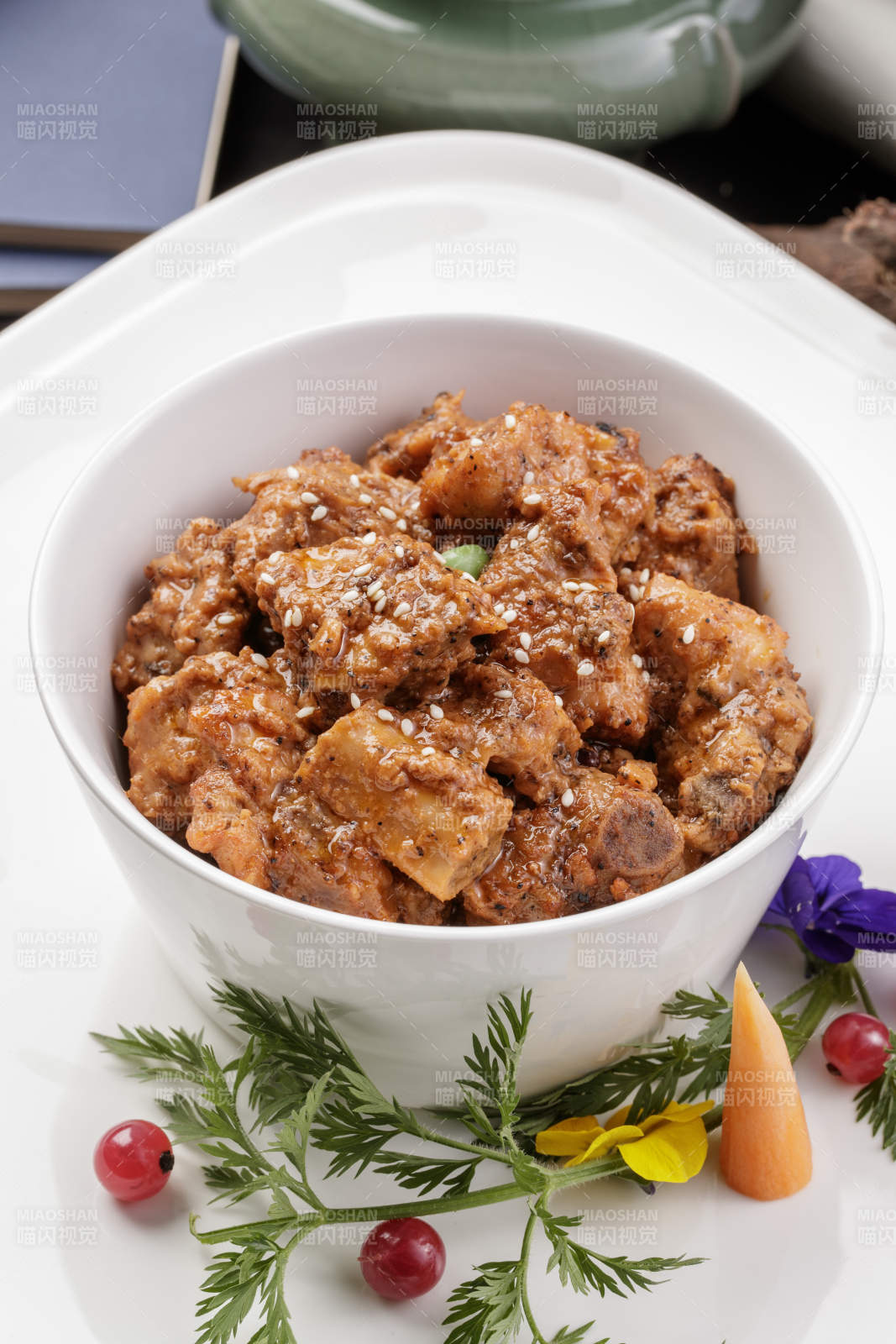 白色瓷碗装的黑胡椒猪小排摆放在黑色背景上图片