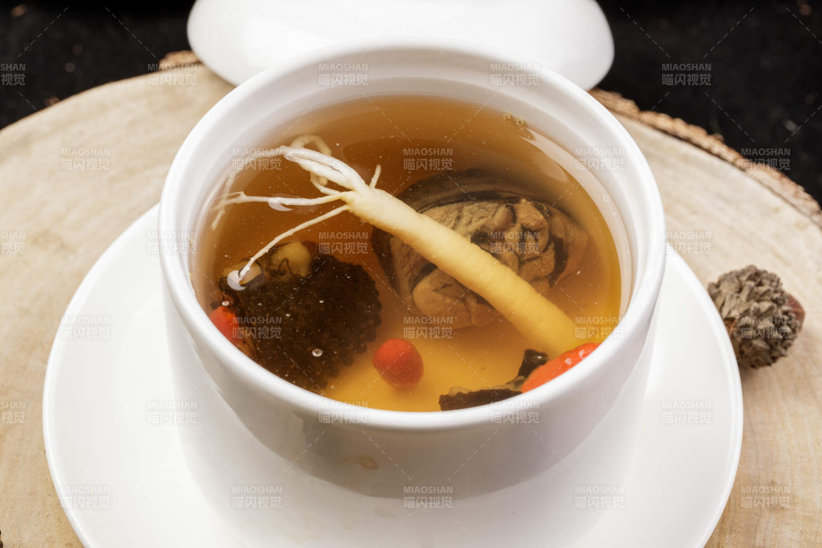 白色汤盅装的羊肚菌人参汤摆放在樟木砧板上图片