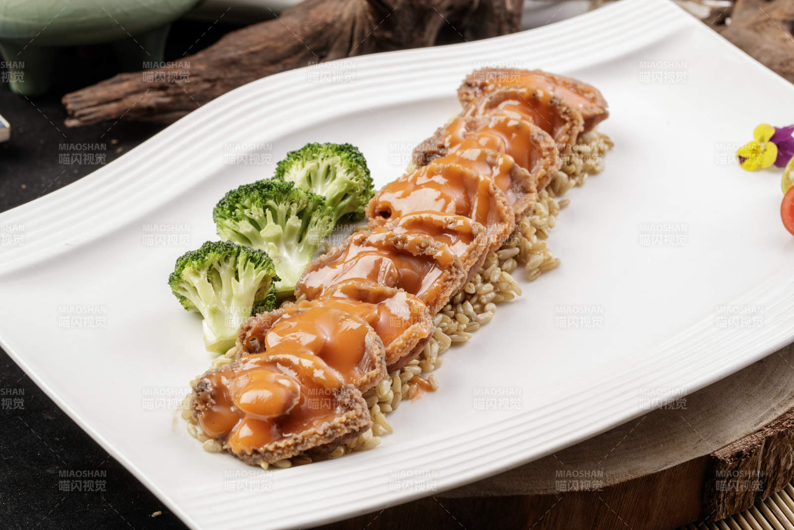 长方形瓷盘装的浓汁薏米鲜鲍鱼摆放在樟木砧板上图片