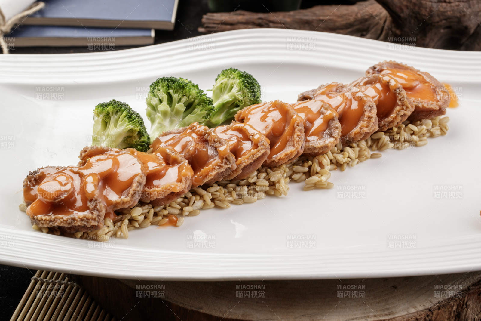 长方形瓷盘装的浓汁薏米鲜鲍鱼摆放在樟木砧板上图片