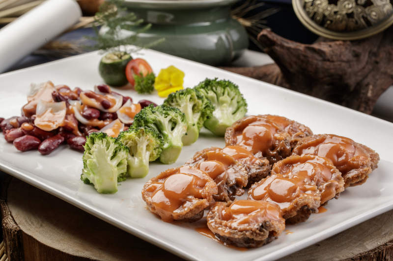 长方形瓷盘装的百合红豆浓汁薏米鲜鲍鱼摆放在樟木砧板上图片