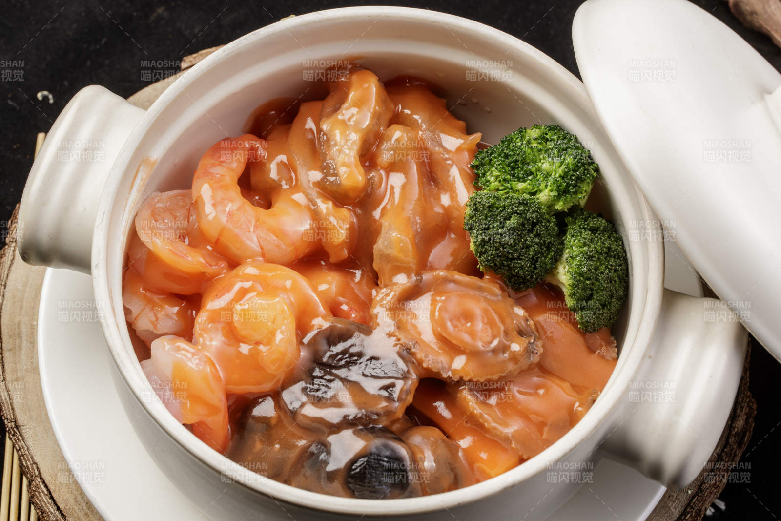 白色瓷砂锅装的浓汤海鲜煲摆放在寿司帘图片