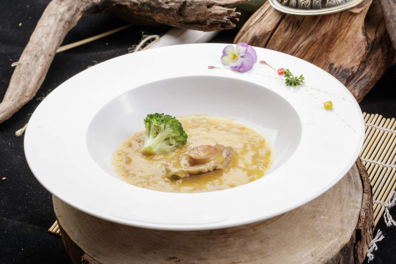 圆形白瓷盘装的薏米鲍鱼羹摆放在樟木砧板上图片