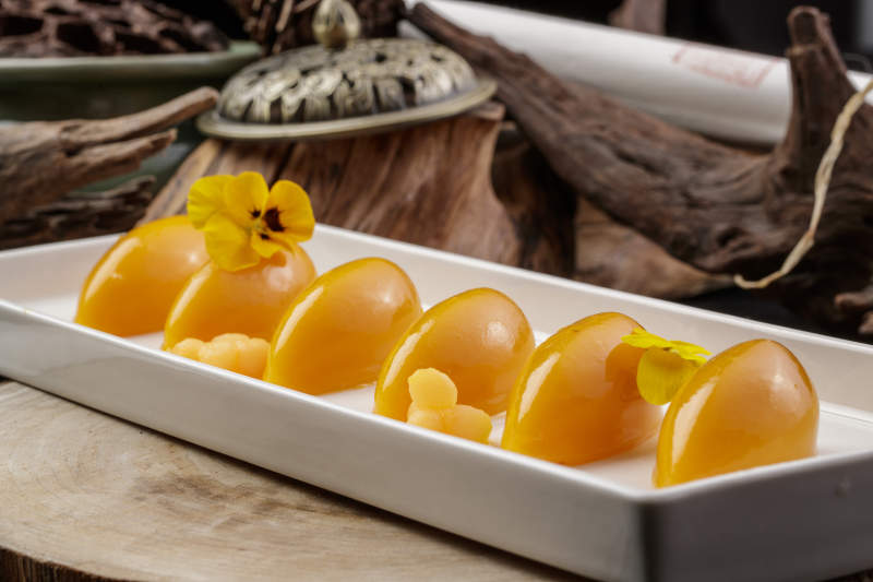 长方形瓷盘装的芒果冻摆放在樟木砧板上图片