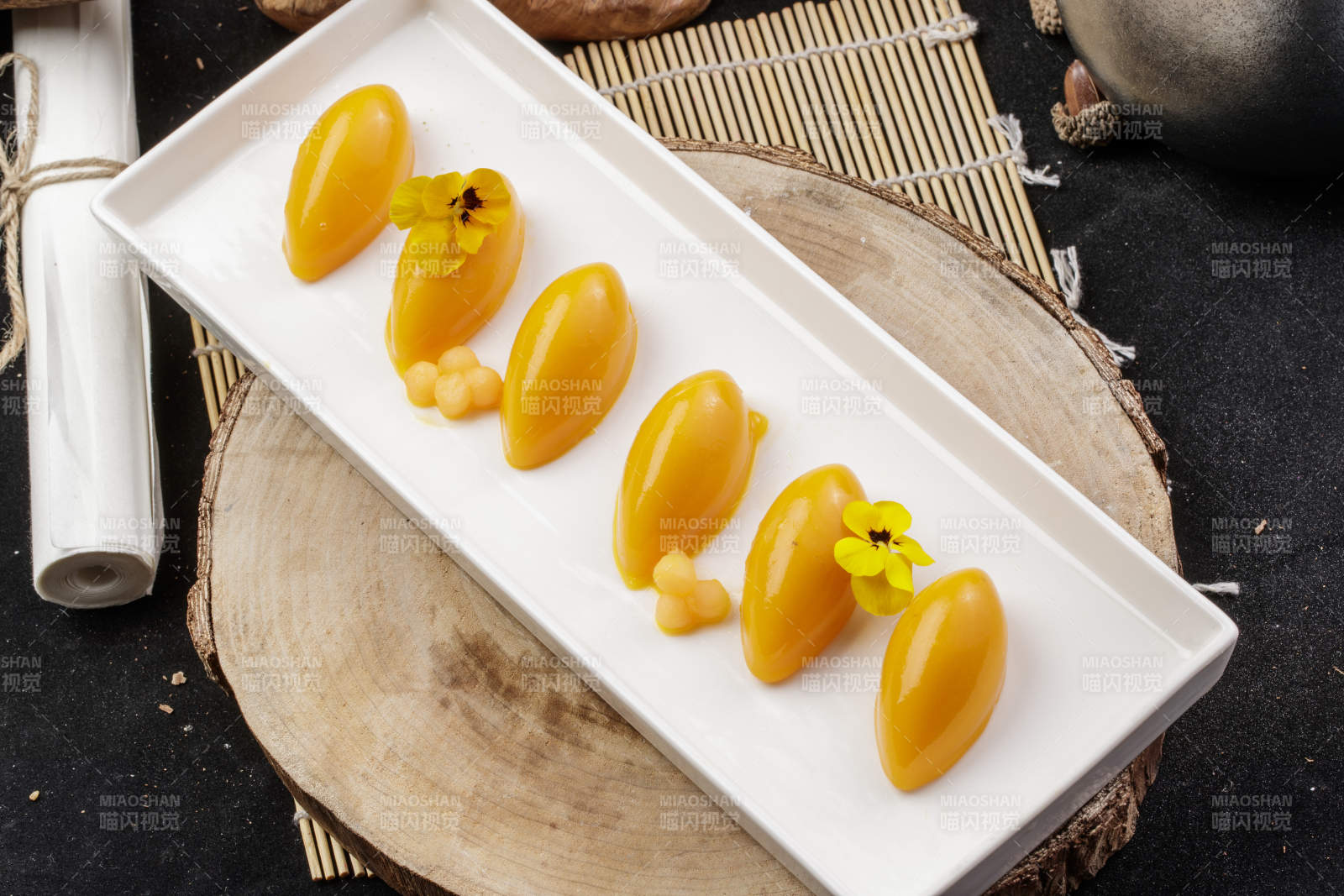 长方形瓷盘装的芒果冻摆放在樟木砧板上图片
