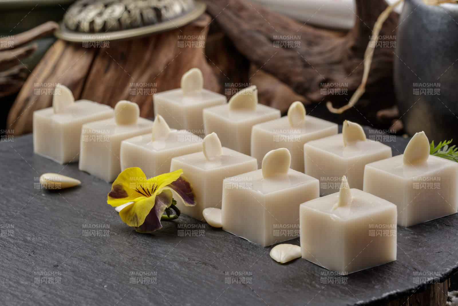 圆形黑色石盘装的奶香杏仁糕摆放在寿司帘上图片