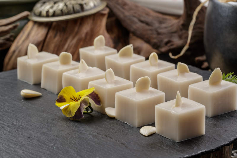 圆形黑色石盘装的奶香杏仁糕摆放在寿司帘上图片