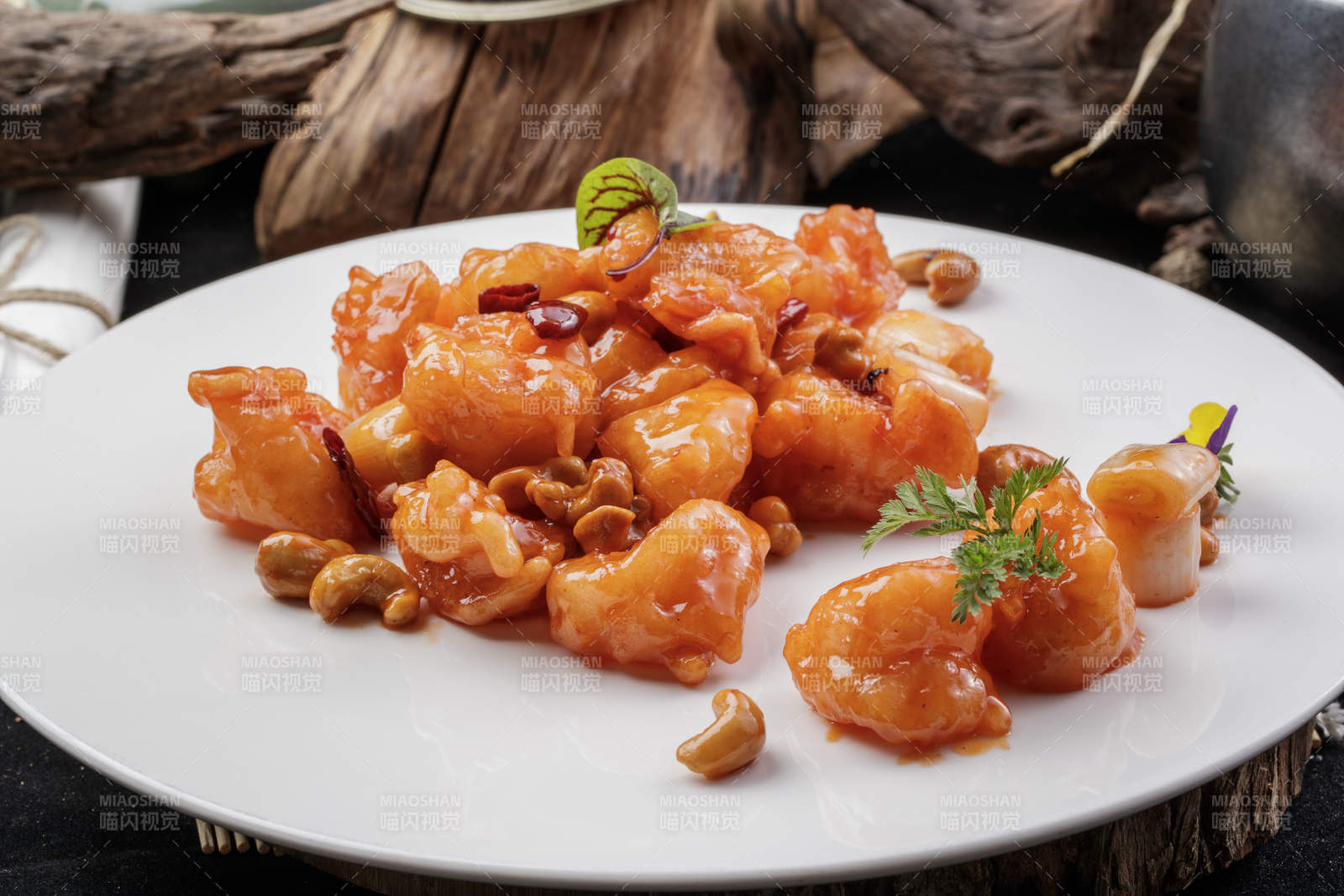 白色圆盘装的宫保大虾球摆放在寿司帘上图片