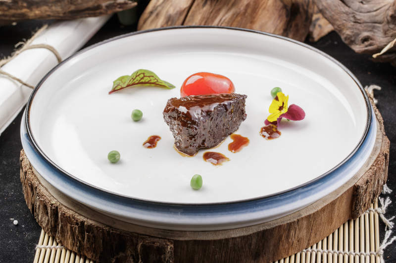 圆形瓷盘装的一品雪花和牛摆放在寿司帘上图片