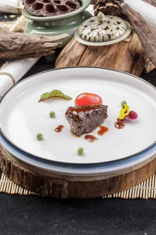 圆形瓷盘装的一品雪花和牛摆放在寿司帘上图片