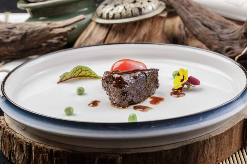 圆形瓷盘装的一品雪花和牛摆放在寿司帘上图片