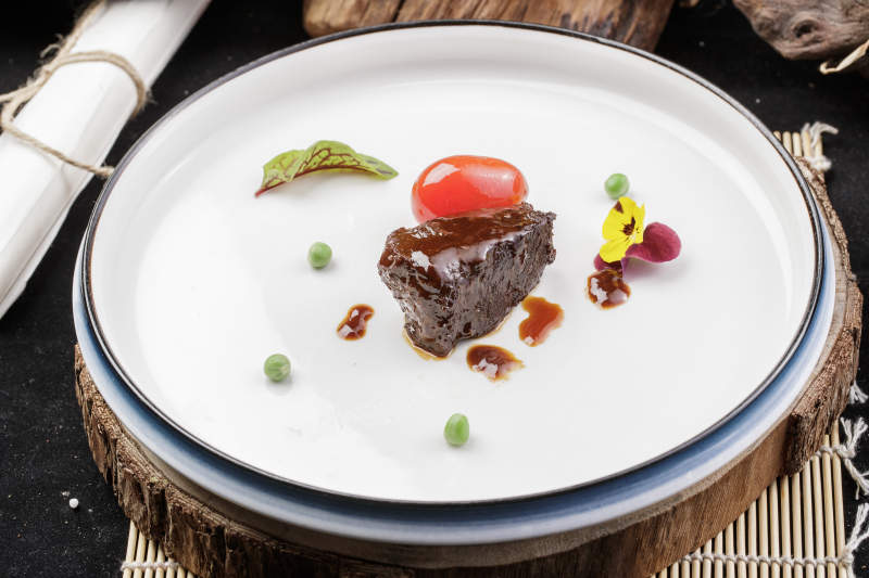 圆形瓷盘装的一品雪花和牛摆放在寿司帘上图片