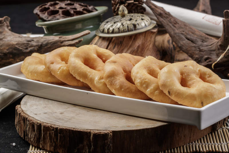 长方形瓷盘装的香炸小油饼摆放在樟木砧板上图片