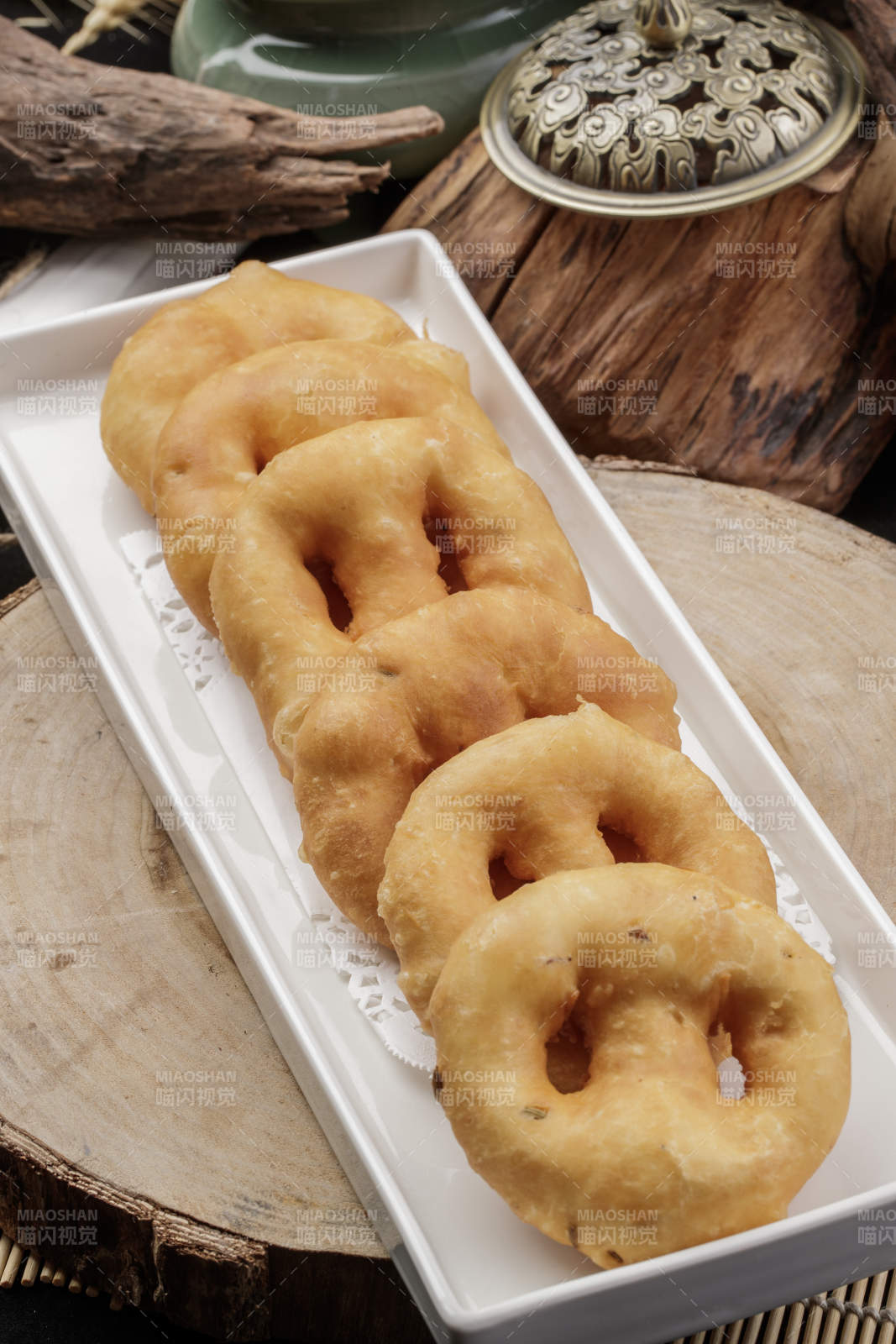 长方形瓷盘装的香炸小油饼摆放在樟木砧板上图片