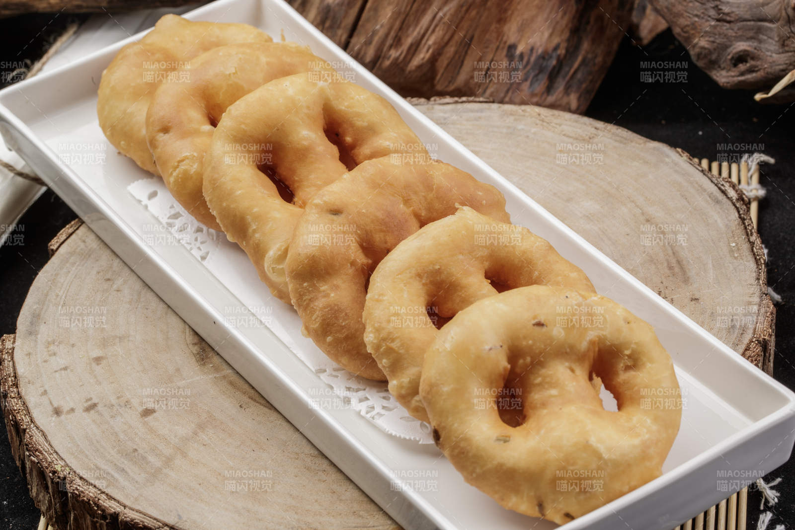 长方形瓷盘装的香炸小油饼摆放在樟木砧板上图片