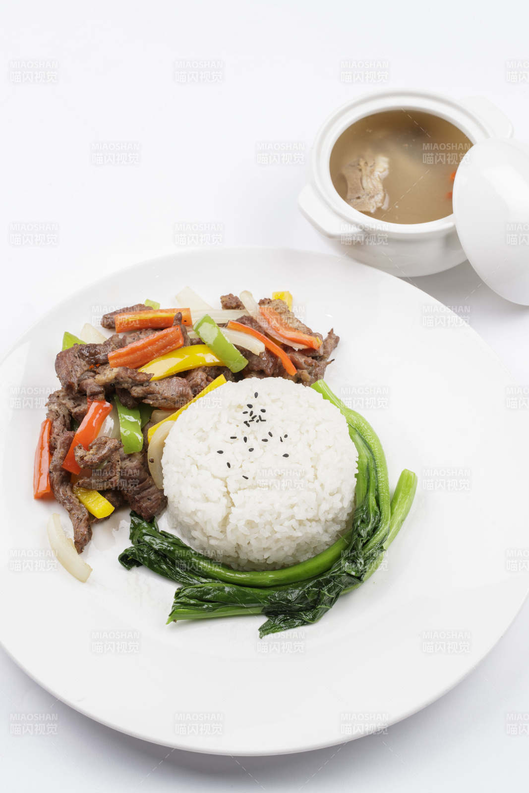 白色瓷盘装的杭椒彩椒牛柳盖饭图片