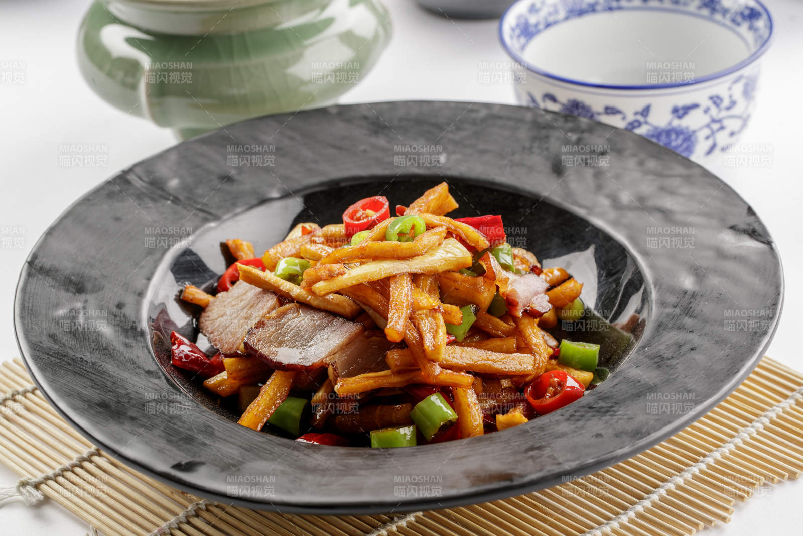 黑色石盘装的菜菔炒腊肉图片