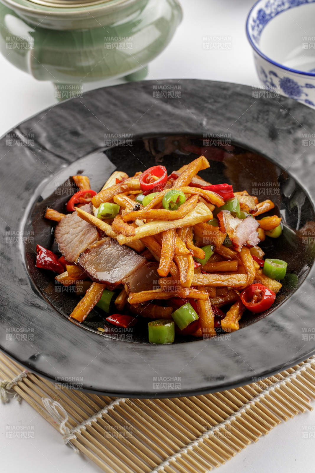 黑色石盘装的菜菔炒腊肉图片