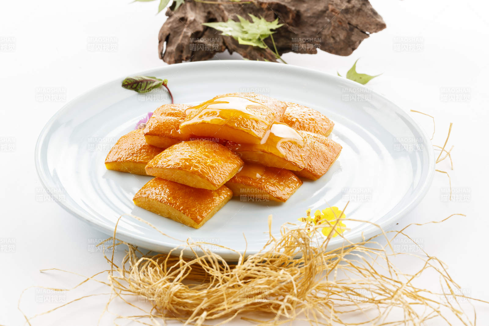 青瓷盘装的蜂蜜焗南瓜摆放在白色背景上图片