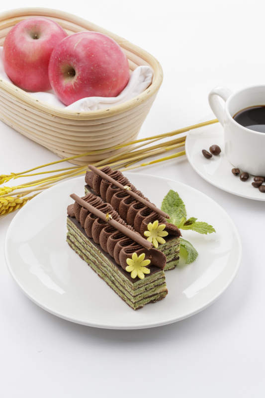 巧克力酱抹茶奶酪慕斯蛋糕摆放在白色背景上图片