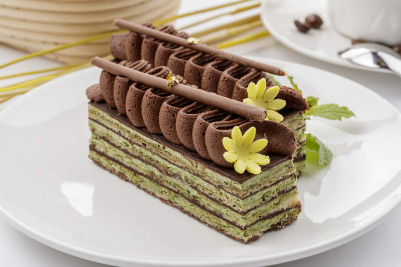 巧克力酱抹茶奶酪慕斯蛋糕摆放在白色背景上图片