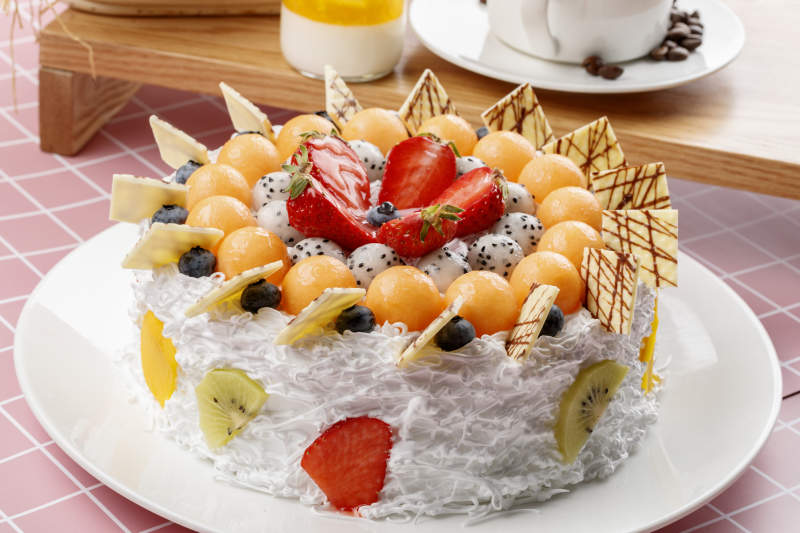 奶油缤纷水果蛋糕摆放在粉色背景上图片