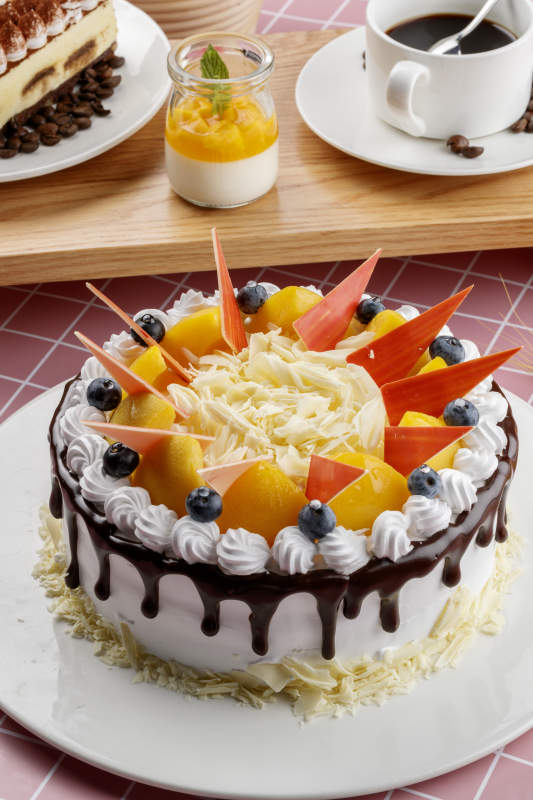 芝士水果奶油巧克力蛋糕摆放在粉色背景上图片