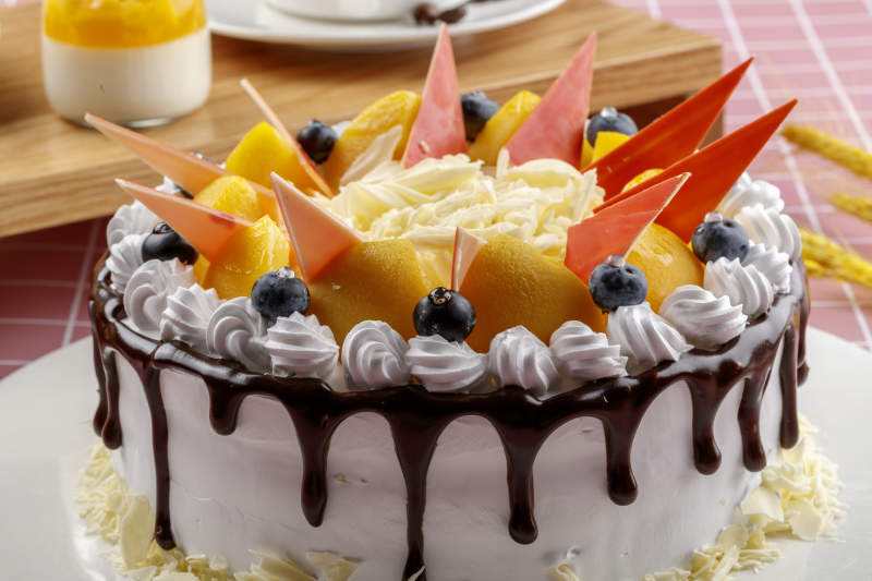 芝士水果奶油巧克力蛋糕摆放在粉色背景上图片