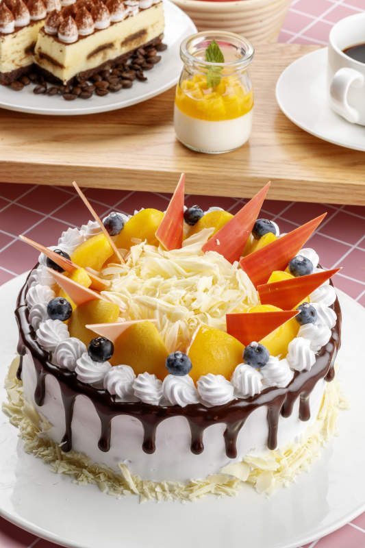 芝士水果奶油巧克力蛋糕摆放在粉色背景上图片