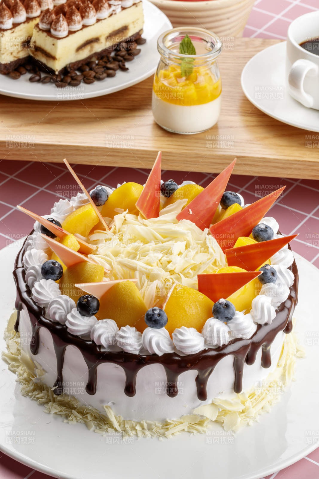 芝士水果奶油巧克力蛋糕摆放在粉色背景上图片