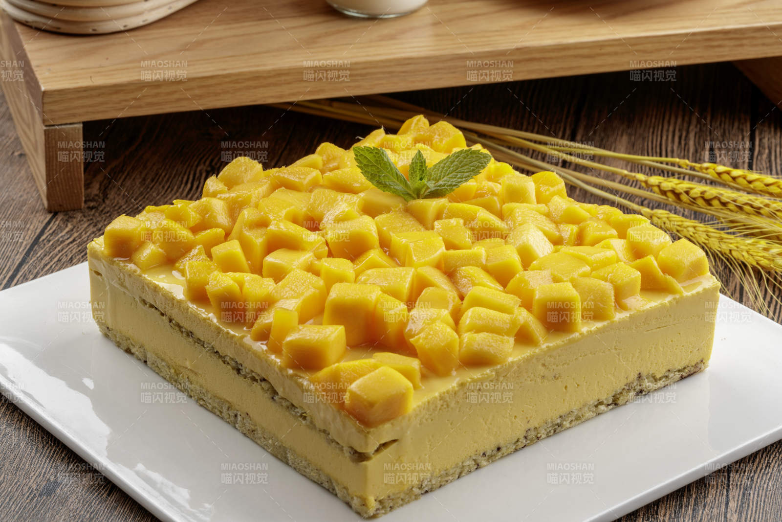 芒果奶油三层蛋糕摆放在木纹底板上图片