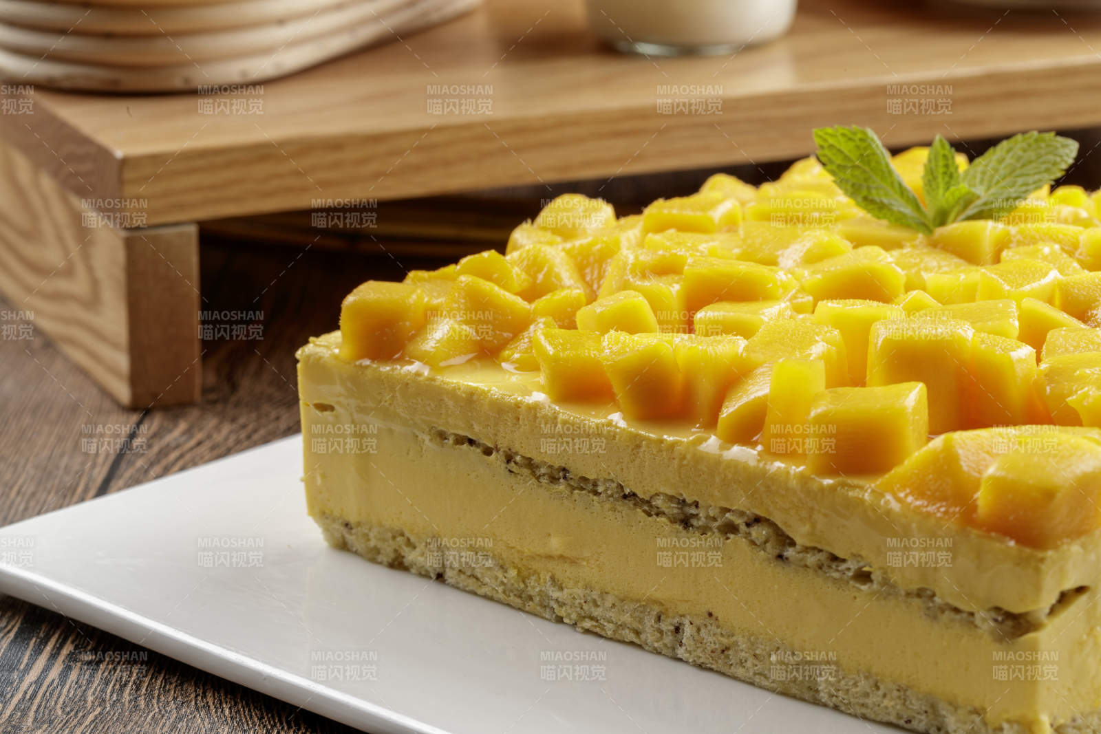 芒果奶油三层蛋糕摆放在木纹底板上图片