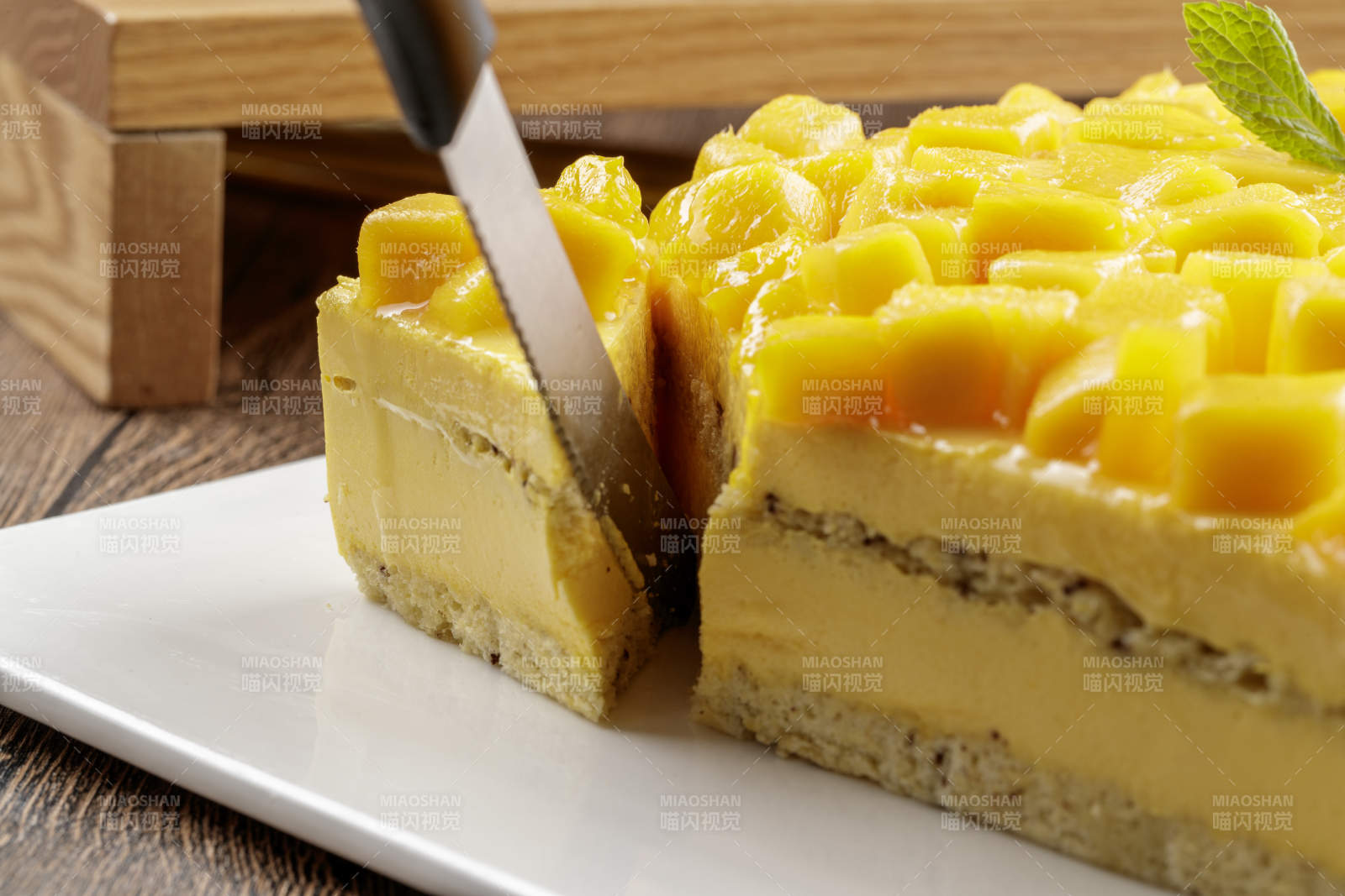 芒果奶油三层蛋糕摆放在木纹底板上图片