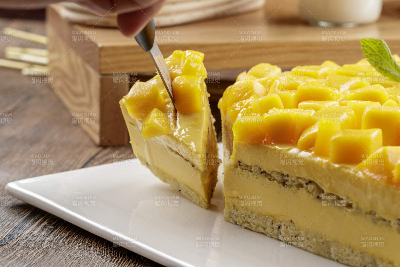 芒果奶油三层蛋糕摆放在木纹底板上图片