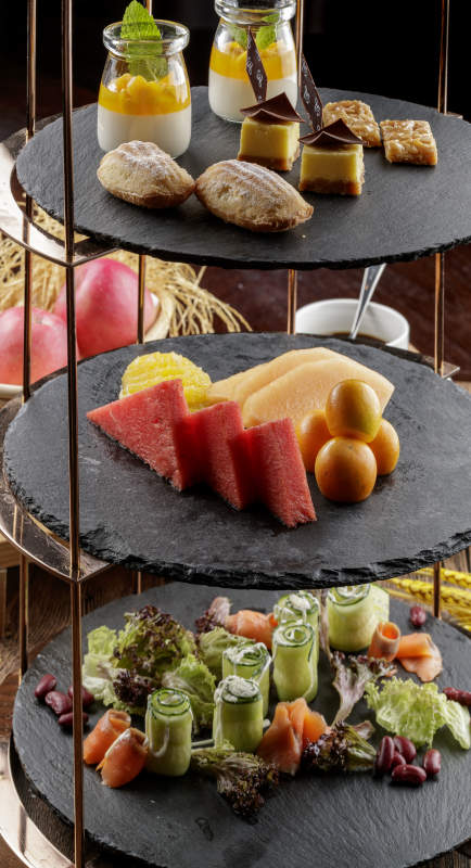 芒果奶油三层蛋糕摆放在木纹底板上图片