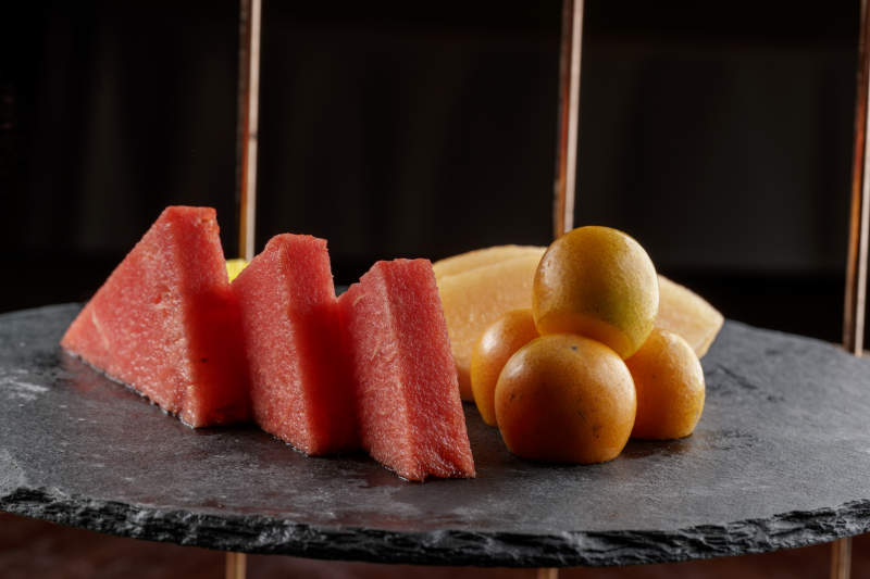 圆形黑色石板装的甜品全拼摆放在黑色背景上图片