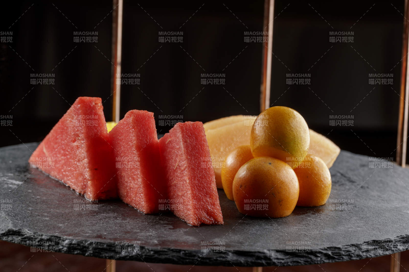 圆形黑色石板装的甜品全拼摆放在黑色背景上图片