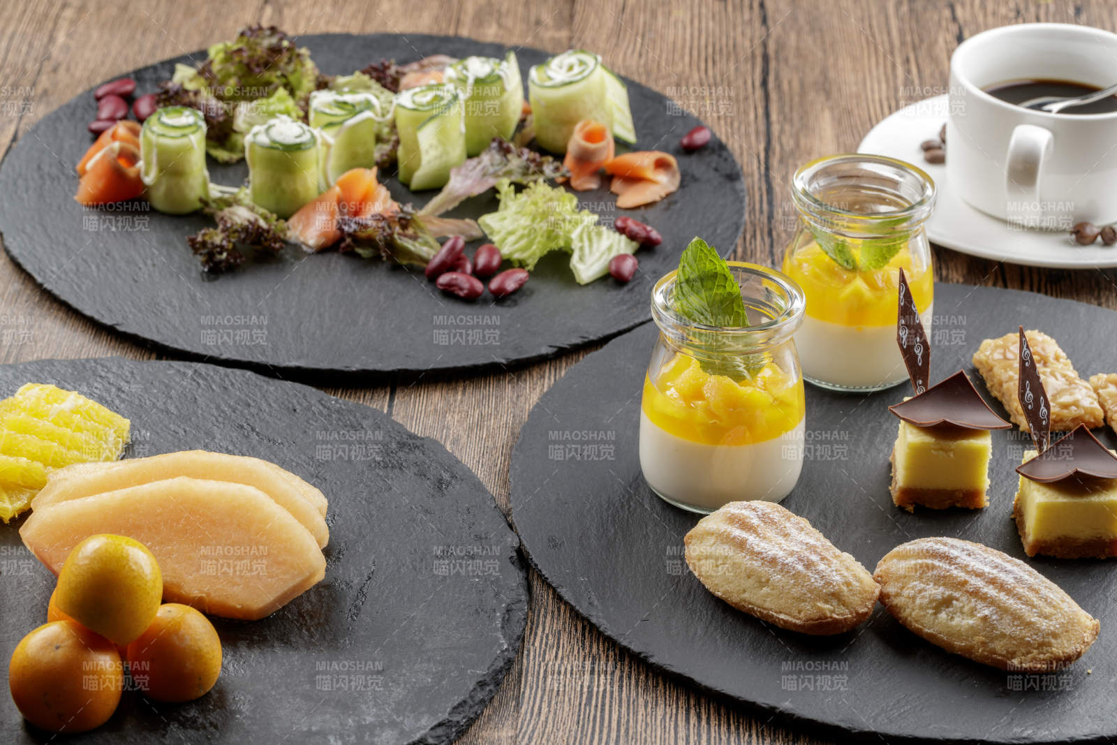 圆形黑色石板装的甜品全拼摆放在黑色背景上图片