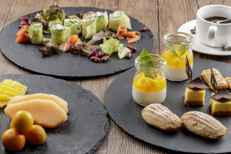 圆形黑色石板装的甜品全拼摆放在黑色背景上图片