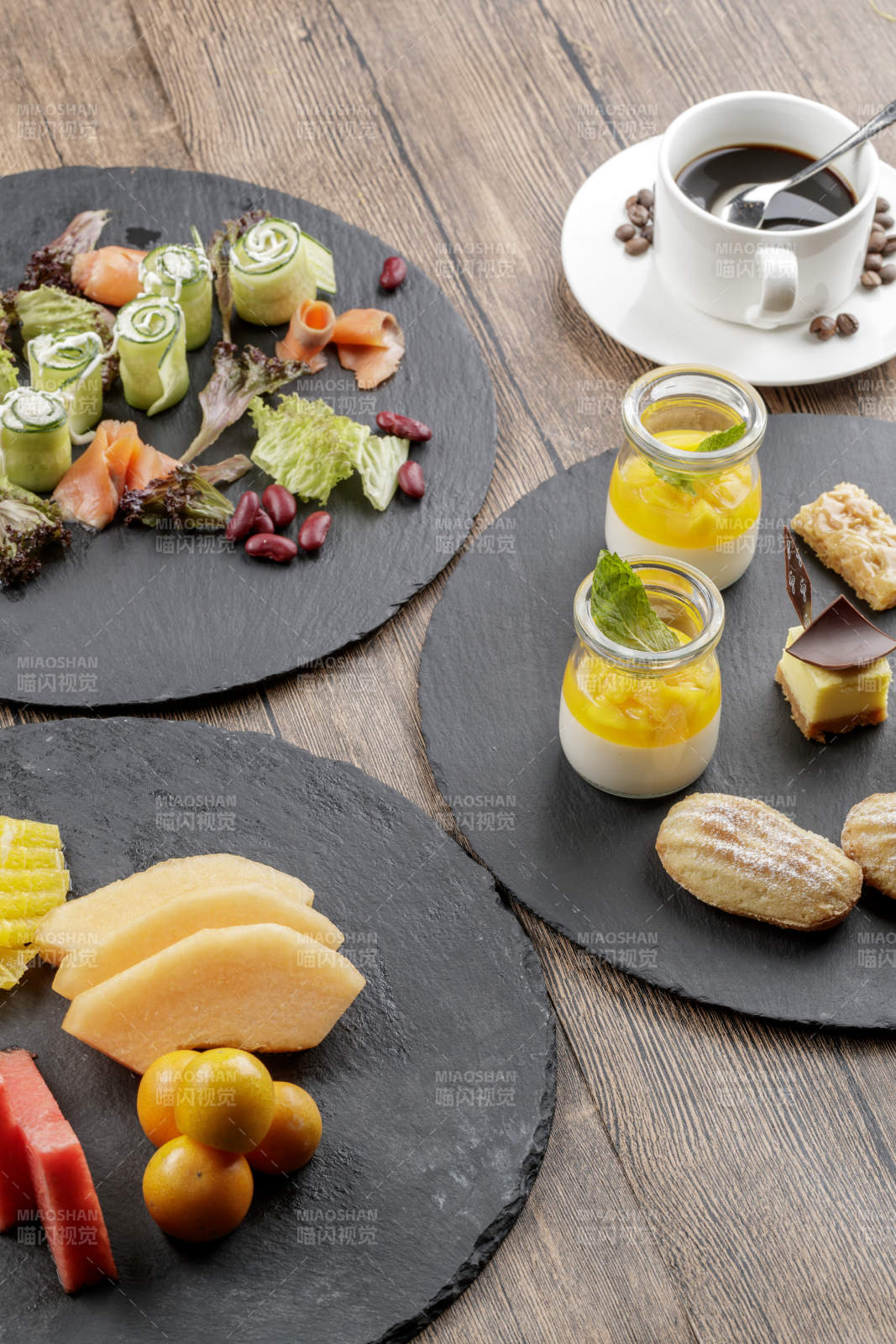 圆形黑色石板装的甜品全拼摆放在黑色背景上图片