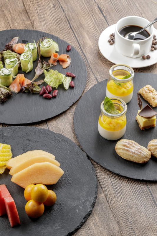 圆形黑色石板装的甜品全拼摆放在黑色背景上图片