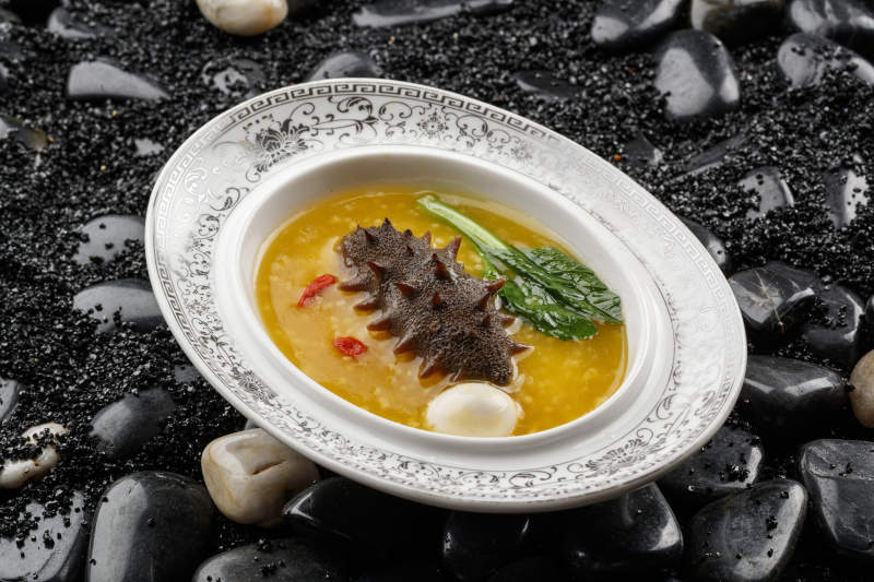 小米炖辽参摆放在黑色鹅卵石上图片